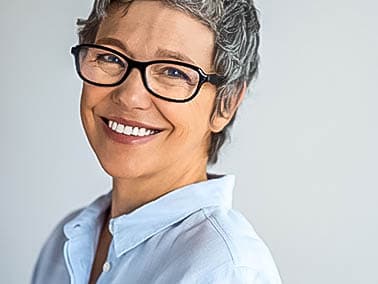 middle aged woman in blue button down and glasses smiling