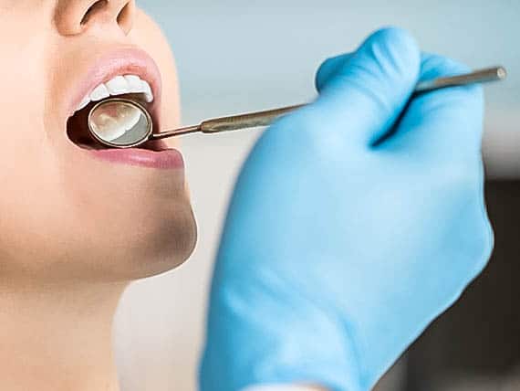 dentist using mirror to look at patients teeth
