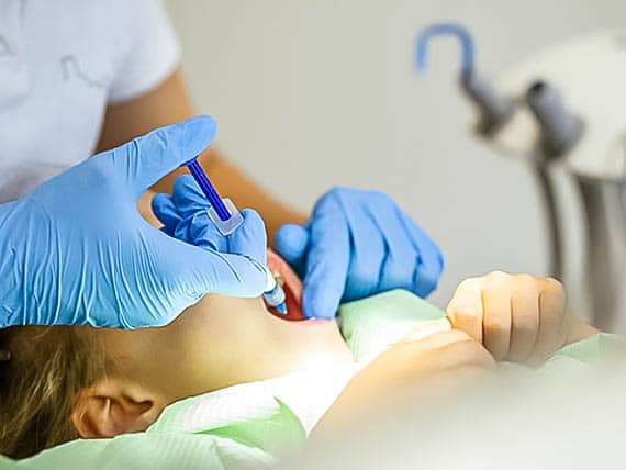 child receiving a numbing shot before dental fillings