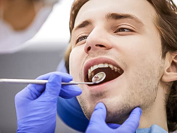 dentist evaluating patients teeth with dental mirror