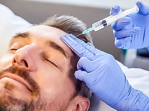 male patient being administered a syringe in the forehead