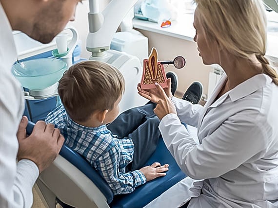 dentist explaining procedure to child and parent