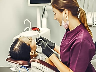 female dental hygienist performing a dental cleaning