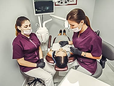 two dental hygienists assisting with a tooth extraction