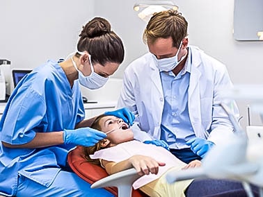 dental hygienist and dentist performing dental cleaning on child