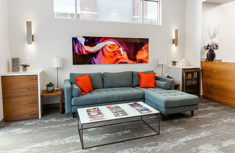 blue l-shaped couch and white coffee table in arete smile design waiting room