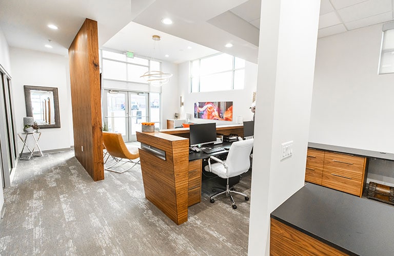 waiting room with grey carpet and a modern wood receptionist desk